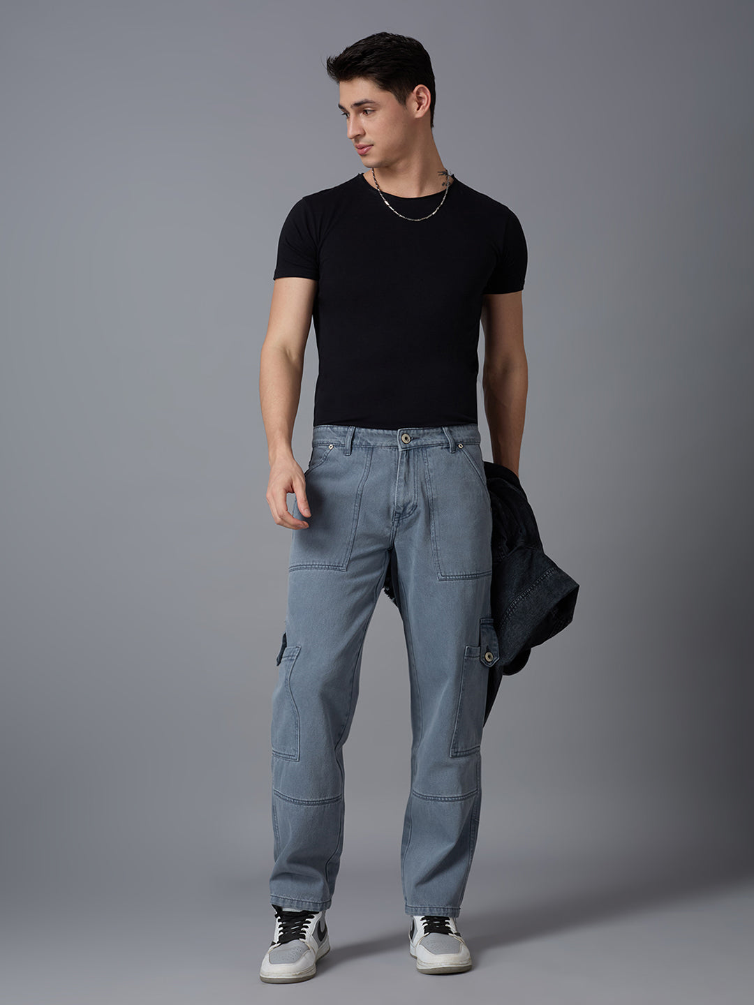 Model styling TCI Men's Dark Grey Denim Cargo Pants with a Black T-Shirt & Sneakers - Fashionable Streetwear Look