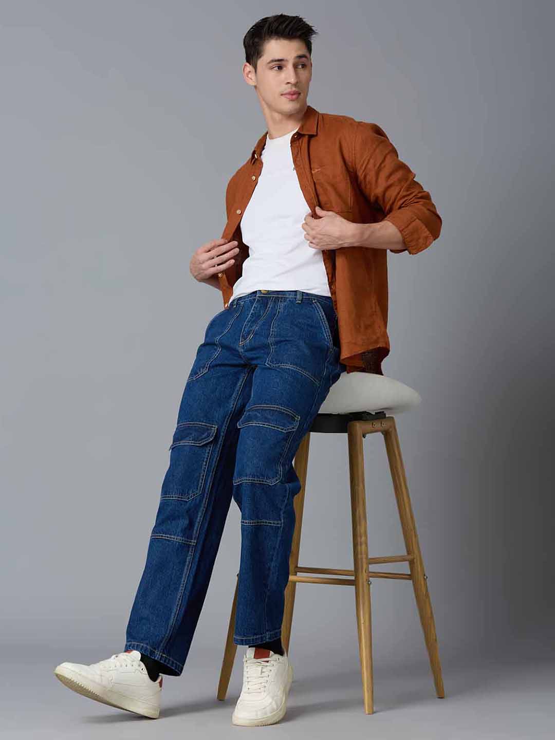 Model styling TCI Men's Ink Blue Denim Cargo Pants with a Brown Shirt & Sneakers - Trendy Streetwear Look