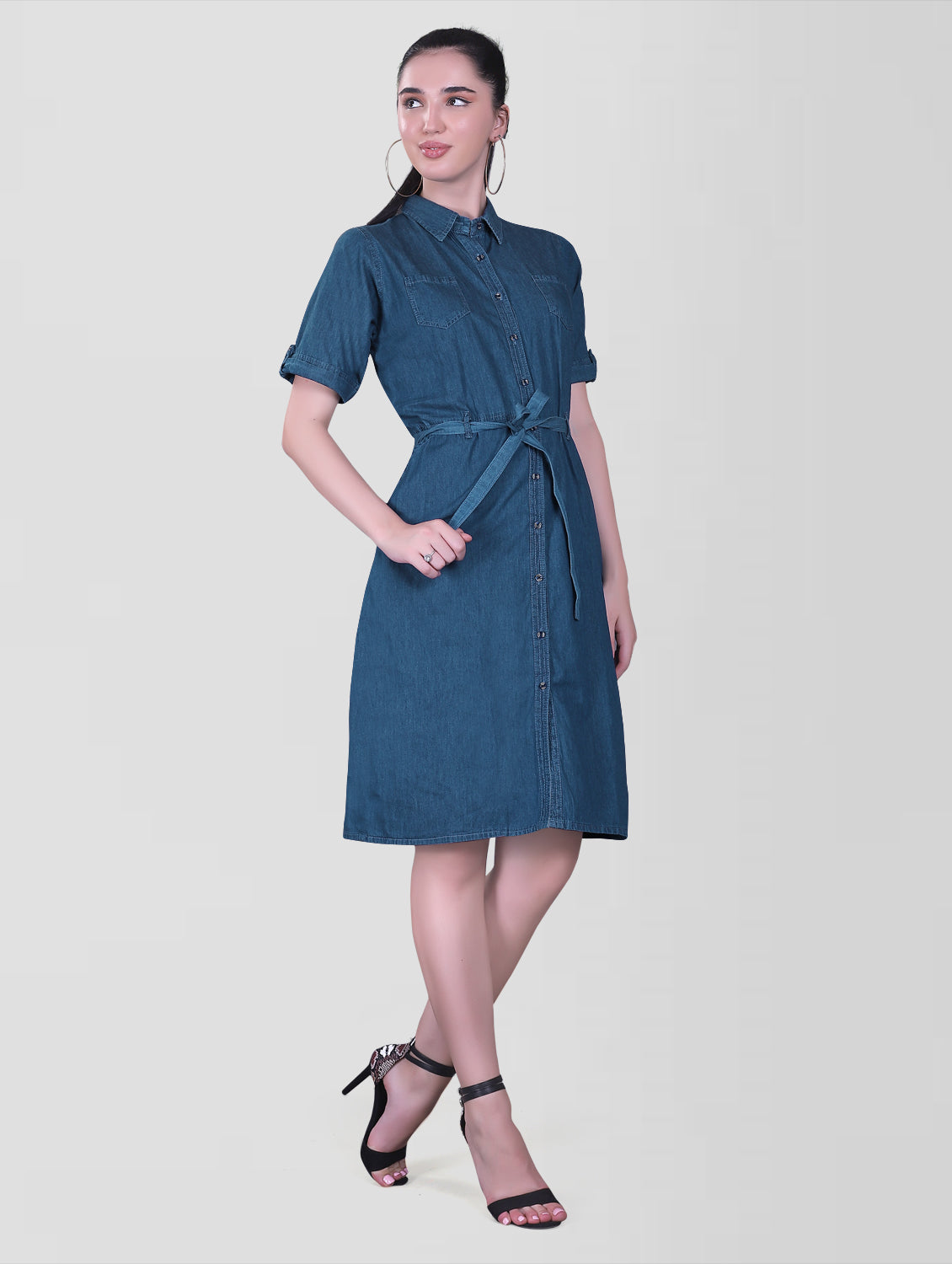 Side view of the Cefalu Women’s Blue Denim Dress showing the A-line silhouette and below-knee length. The dress is made from comfortable blue denim with two side pockets.