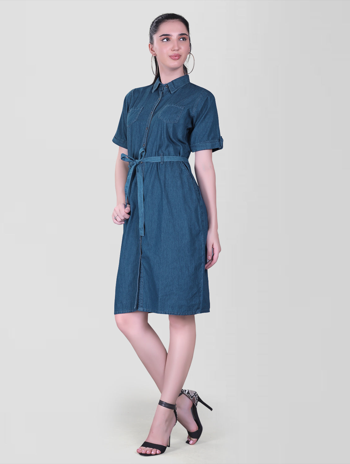 Model wearing the Cefalu Women’s Blue Denim Dress in a casual setting, demonstrating the dress’s fit and style. The A-line midi dress features a shirt collar, half sleeves with luppi, and a soft blue denim finish.